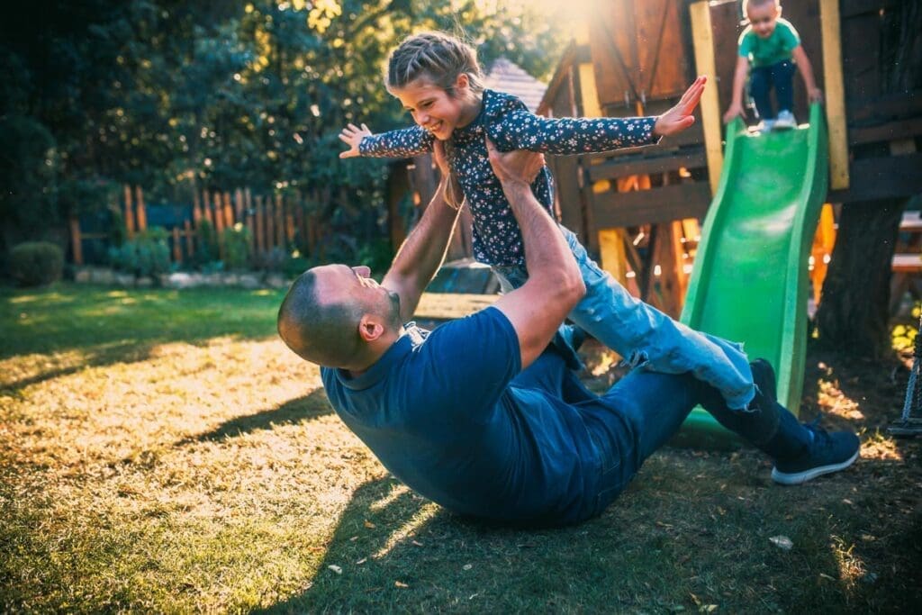 Happy dad and daughter enjoying time together next to a slide.