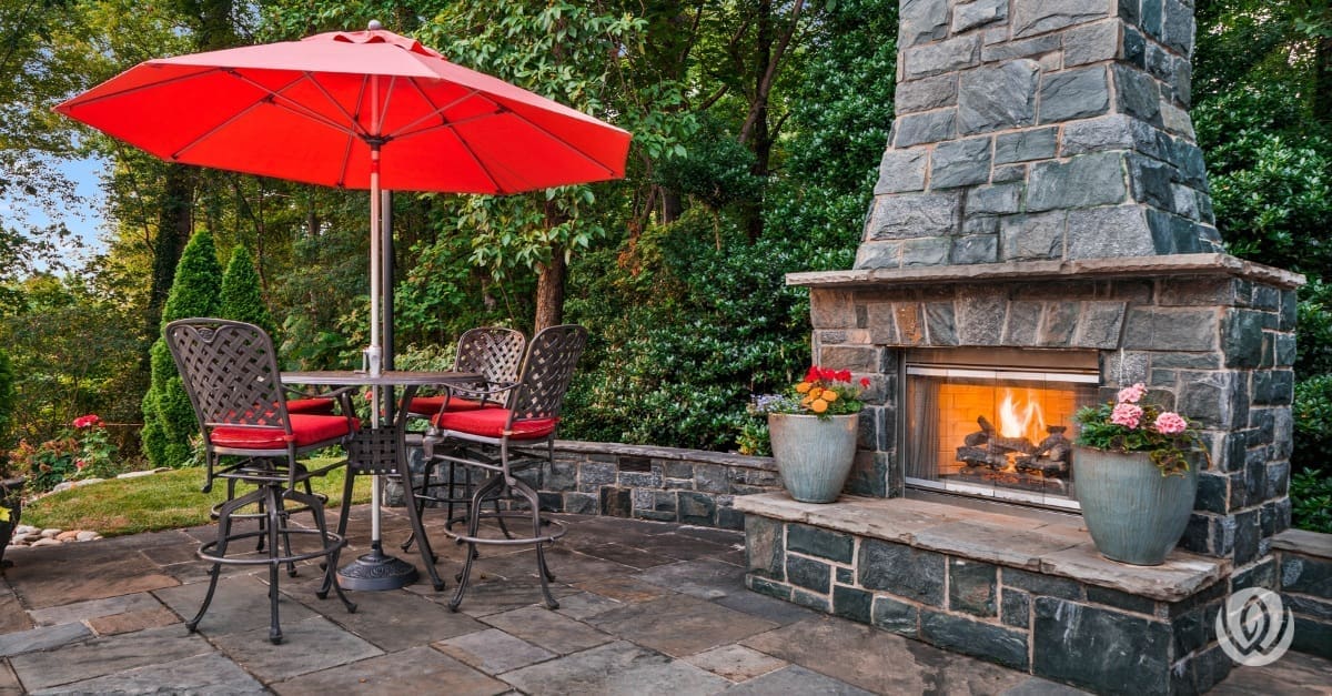 Stone outdoor fireplace next to backyard dining area
